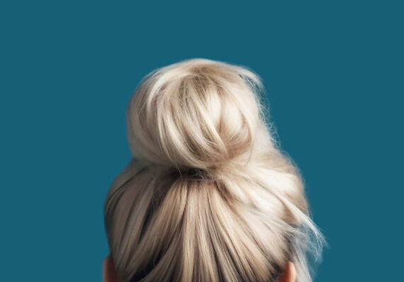 Modern hairstyle bun on blonde hair back view close-up.