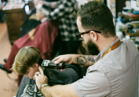 Hairstylist cutting young man's hair in a wet mop TikTok haircut
